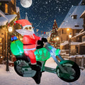 Inflatable Santa riding a green motorcycle on a snowy village street