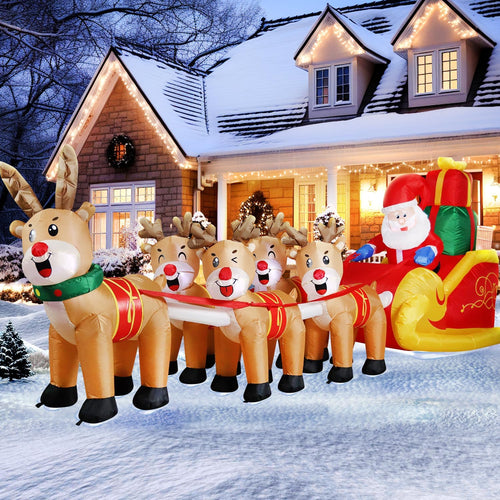 Long inflatable Santa sleigh pulled by five reindeer across a snowy lawn